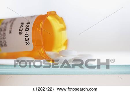 Stock Photo - Close up of pills spilling out of medication bottle. Fotosearch