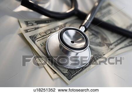 Stock Image - Close up of stethoscope and US dollars. Fotosearch