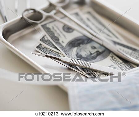 Stock Image - Close up of surgical tools and money. Fotosearch