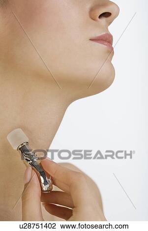 Stock Image - Close up of woman applying perfume to neck. Fotosearch