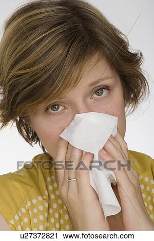Stock Image - Close up of woman blowing nose. Fotosearch