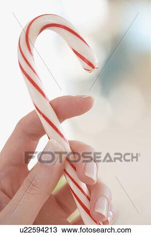 Stock Image - Close up of woman holding candy cane. Fotosearch