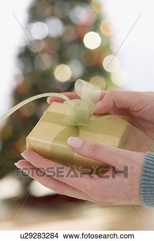 Picture - Close up of woman holding Christmas gift. Fotosearch