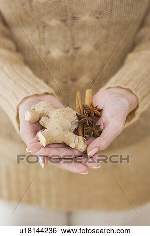 Stock Photograph - Close up of woman holding ginger root and spices. Fotosearch