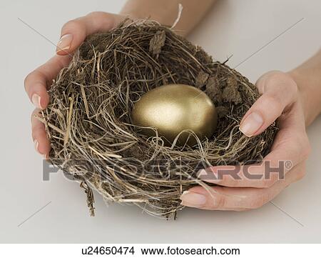 Picture - Close up of woman holding nest with golden egg. Fotosearch