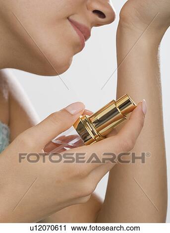 Close up of woman holding perfume and smelling wrist View Large Photo Image Stock Image - Close up of woman holding perfume and smelling wrist. Fotosearch