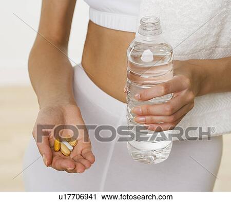 Close up of woman holding vitamins and bottle of water View Large Photo Image Stock Image - Close up of woman holding vitamins and bottle of water. Fotosearch