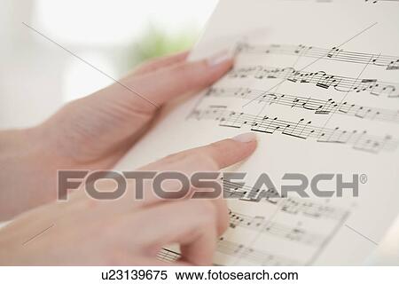 Stock Photography - Close up of woman pointing at sheet music. Fotosearch