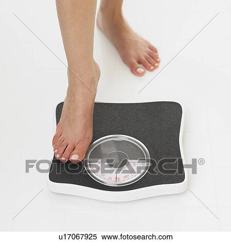 Stock Photography - Close up of woman stepping on scale. Fotosearch
