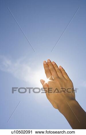 Stock Image - Close up of woman's hand blocking sun. Fotosearch