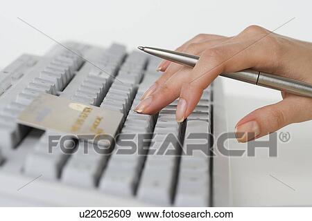 Close up of woman's hand holding pen with credit card and computer keyboard View Large Photo Image Stock Photo - Close up of woman's hand holding pen with credit card and computer keyboard. Fotosearch