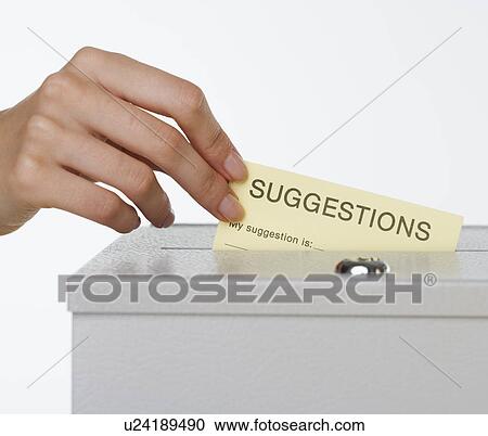 Stock Image - Close up of woman's hand putting card in suggestion box. Fotosearch