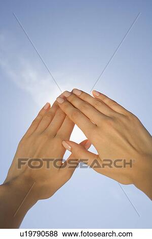 Stock Photo - Close up of woman's hands blocking sun. Fotosearch