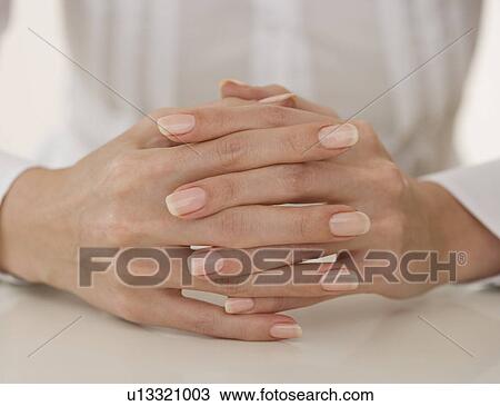 Stock Image - Close up of woman’s hands clasped. Fotosearch