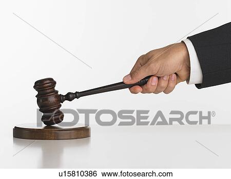 Stock Photograph - Close up studio shot of judge's hand with gavel. Fotosearch