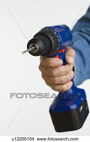 Picture - Close up studio shot of man holding cordless drill. Fotosearch