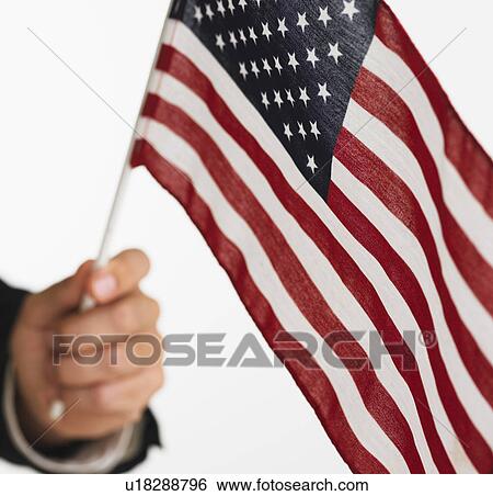 Stock Photograph - Close up studio shot of man holding American flag. Fotosearch