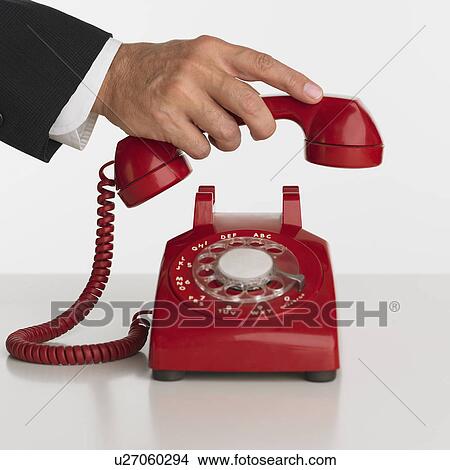 Picture - Close up studio shot of man picking up rotary telephone. Fotosearch