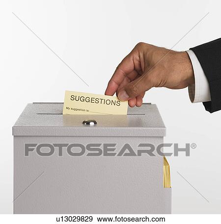 Stock Photo - Close up studio shot of man putting card in suggestion box. Fotosearch