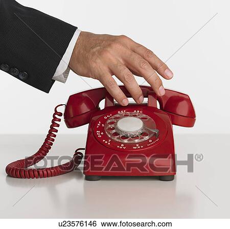 Stock Photograph - Close up studio shot of man reaching for rotary telephone. Fotosearch