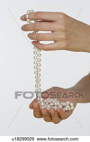 Stock Photo - Close up studio shot of woman's hands holding pearl necklace. Fotosearch