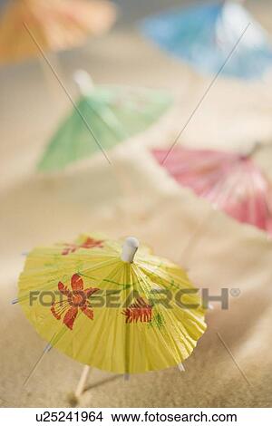 Picture - Cocktail umbrellas in sand. Fotosearch