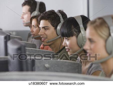 Stock Photo - College students wearing headsets in computer lab. Fotosearch