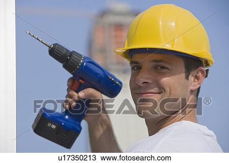 Construction worker holding cordless drill View Large Photo Image Stock Image - Construction worker holding cordless drill. Fotosearch
