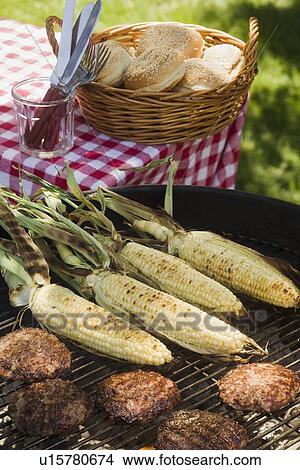 Picture - Corn and hamburgers cooking on grill. Fotosearch