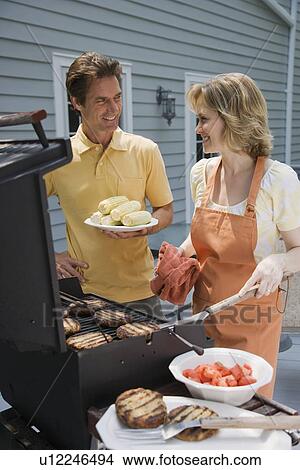Picture - Couple barbequing on deck. Fotosearch