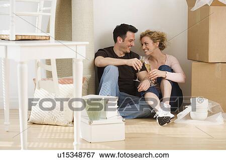 Stock Photo - Couple drinking wine in new house. Fotosearch