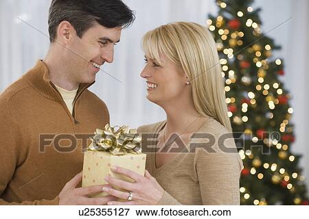 Couple holding Christmas gift View Large Photo Image Stock Photo - Couple holding Christmas gift. Fotosearch