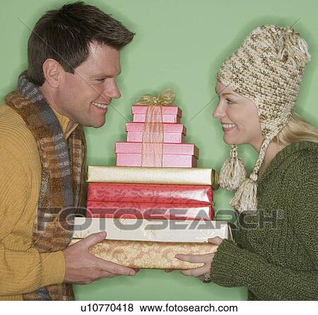 Stock Photo - Couple holding stack of Christmas gifts. Fotosearch