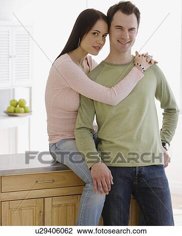 Stock Image - Couple hugging in kitchen. Fotosearch