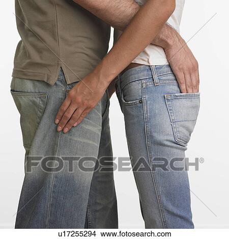 Picture - Couple hugging with man's hand in woman's back pocket. Fotosearch