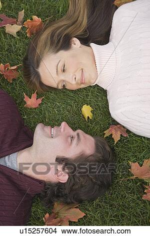 Picture - Couple laying in grass. Fotosearch