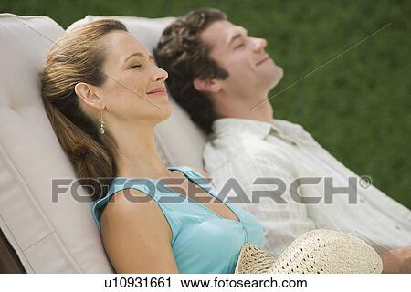 Stock Image - Couple laying in lounge chairs. Fotosearch
