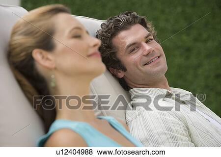 Couple laying in lounge chairs View Large Photo Image Stock Photo - Couple laying in lounge chairs. Fotosearch