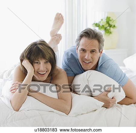 Stock Image - Couple laying on bed. Fotosearch