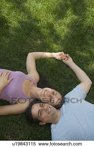 Couple laying with heads together on grass View Large Photo Image Stock Photography - Couple laying with heads together on grass. Fotosearch