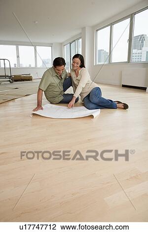 Couple looking at blueprints on floor in new house View Large Photo Image Stock Image - Couple looking at blueprints on floor in new house. Fotosearch
