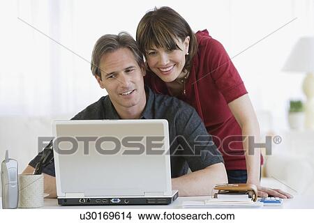 Picture - Couple looking at laptop. Fotosearch