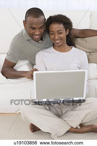 Couple looking at laptop View Large Photo Image Stock Photograph - Couple looking at laptop. Fotosearch