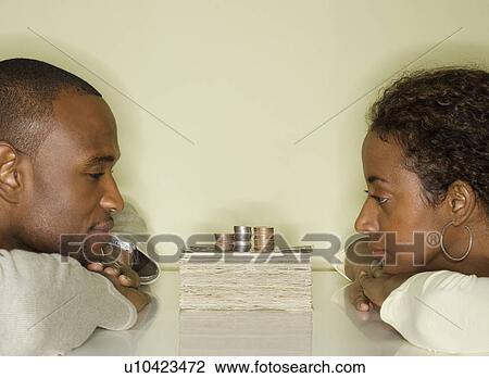 Stock Image - Couple looking at pile of money. Fotosearch
