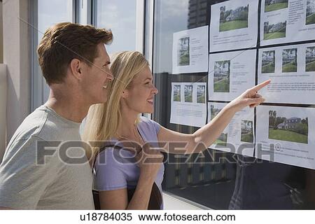 Stock Photography - Couple looking at real estate window. Fotosearch
