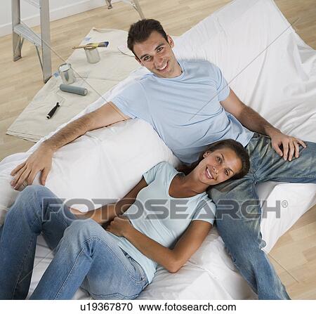 Couple on sofa with paint cans and paintbrushes on floor View Large Photo Image Stock Image - Couple on sofa with paint cans and paintbrushes on floor. Fotosearch