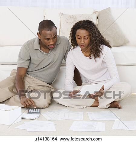 Picture - Couple paying bills on floor. Fotosearch