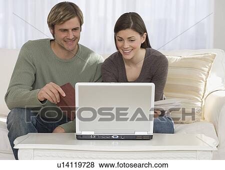 Couple paying bills on laptop View Large Photo Image Stock Photo - Couple paying bills on laptop. Fotosearch