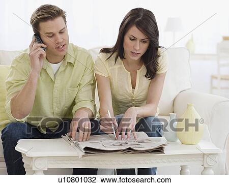 Stock Image - Couple reading classifieds in newspaper. Fotosearch