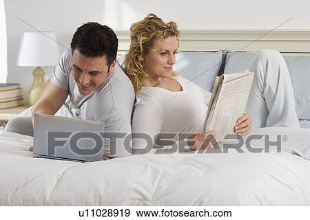Couple relaxing on bed View Large Photo Image Stock Photo - Couple relaxing on bed. Fotosearch